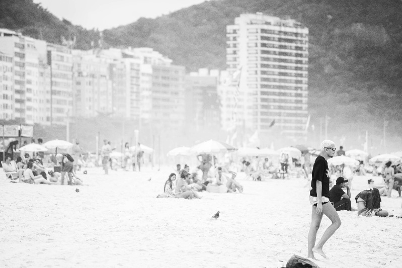 A lot of people on the beach with tall buildings in the background and smog hanging in the air.